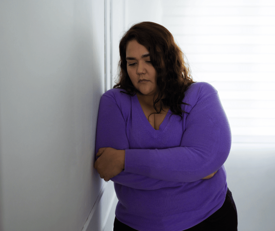 Einsame, übergewichtige Frau an die Wand gelehnt.