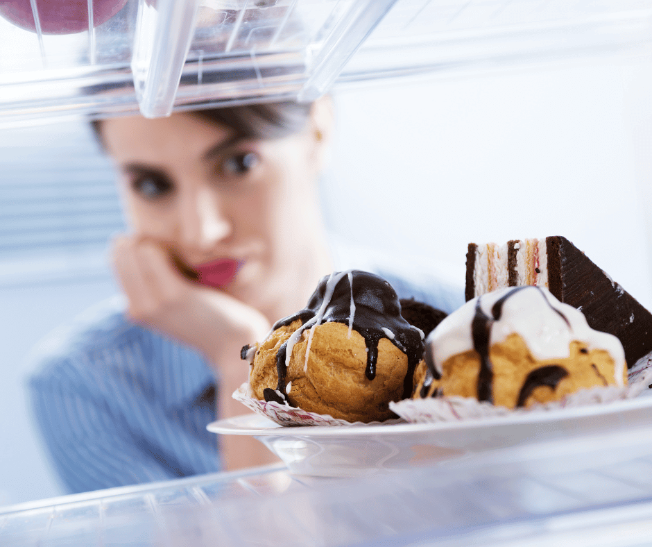 Eine Frau, die im Kühlschrank leckeres Essen sieht und nur schwer verzichten kann.