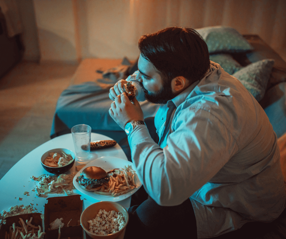 Mann isst zu viel Junkfood auf dem Sofa vor dem TV