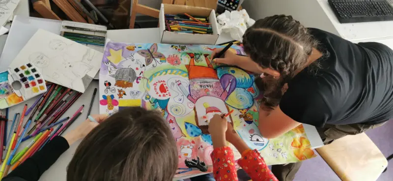 Kinder malen ein gemeinsames, buntes Bild