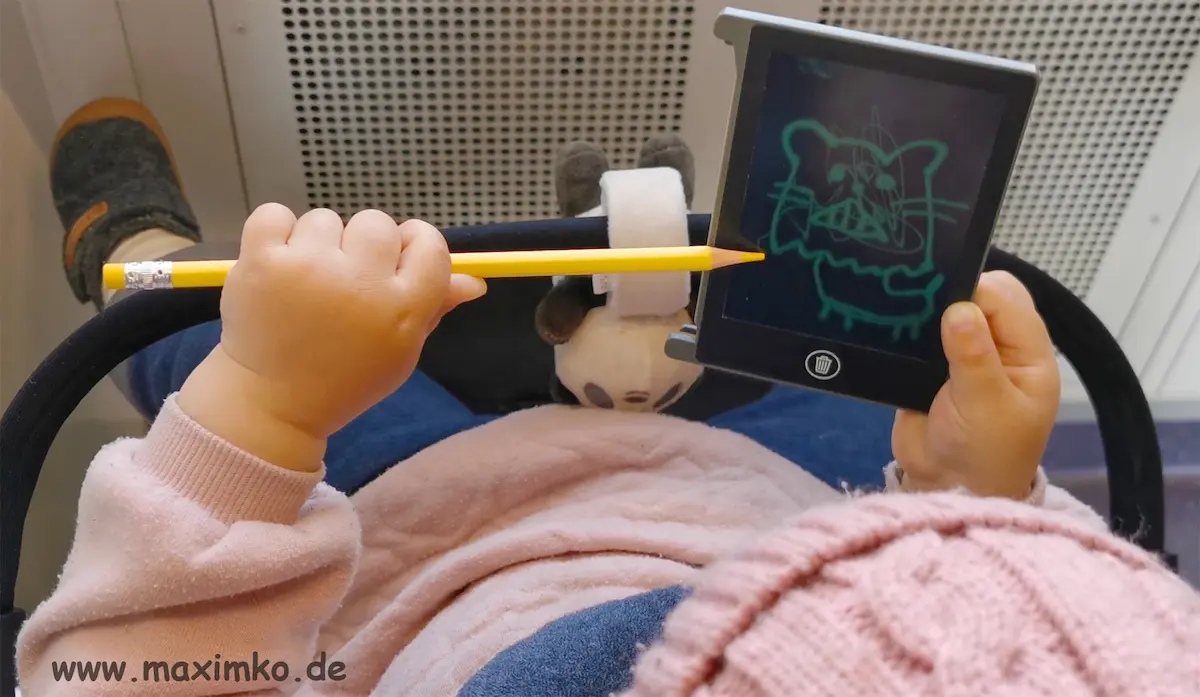 Kleinkind sitzt im Kinderwagen in einer U-Bahn und zeichnet auf einem kleinen digitalen LCD-Zeichenbrett.