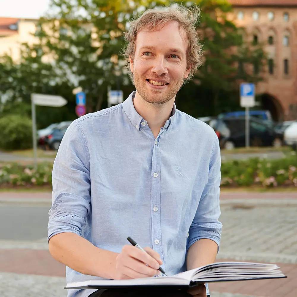 foto von maxim simonenko mit einem skizzenblock und zeichenstift in der hand