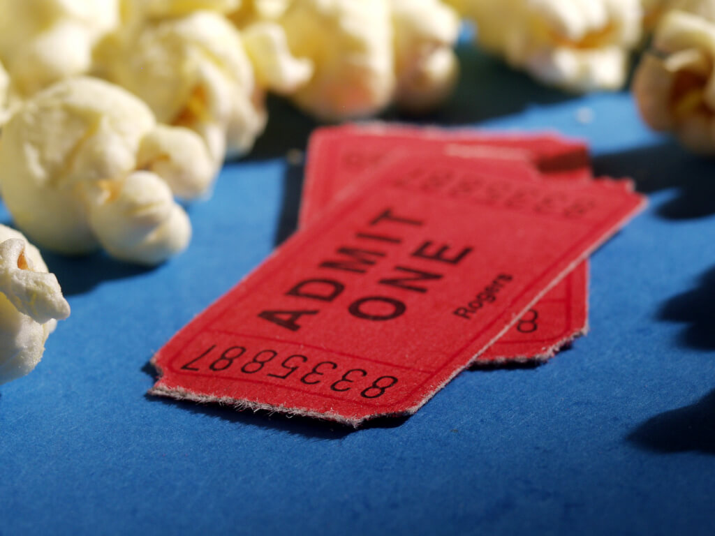 Two red cinema tickets surrounded by popcorn