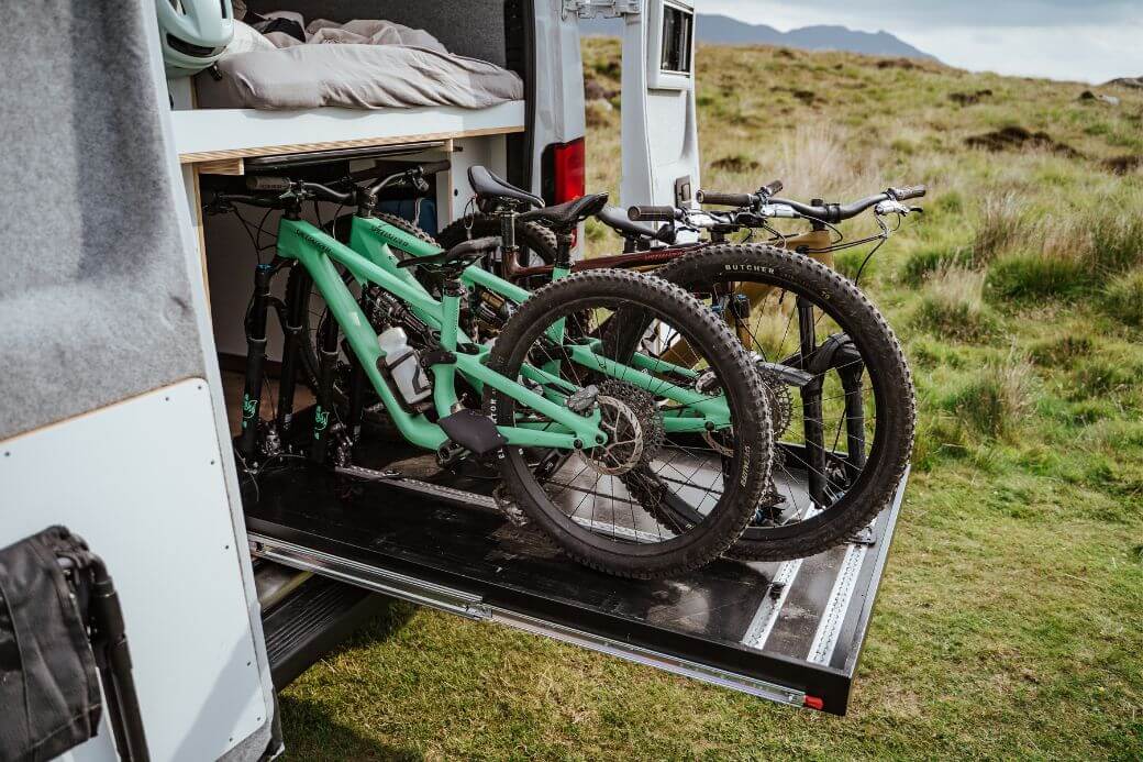 Seitenansicht: vier Mountainbikes nebeneinander auf Heckauszug im Camper