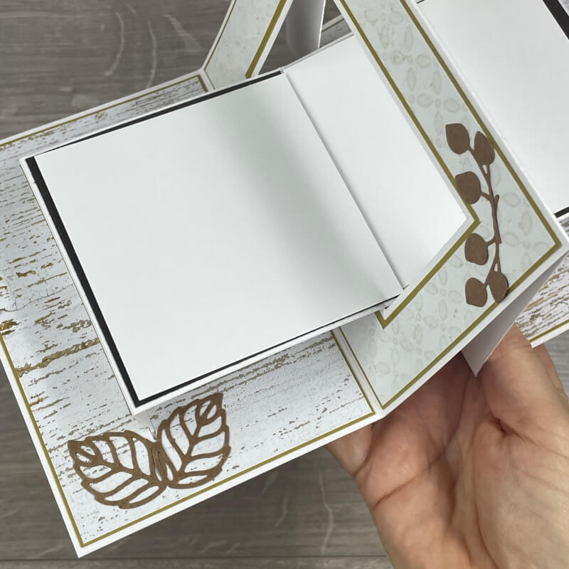 Detail innen: die Schreibfläche in Grundweiß zum Aufklappen, daneben Stanzteile in Espresso auf Holzoptik-Papier