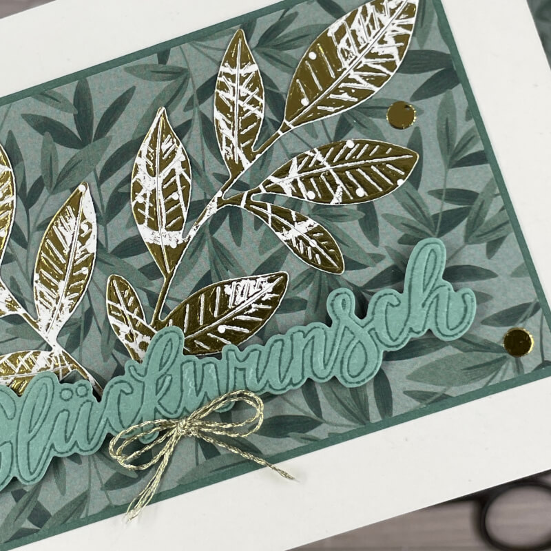 Nahaufnahme der einfachen Kartenversion mit goldgeprägten Blättern, mintgrünem Schriftzug 'Glückwunsch' und goldener Kordelschleife.