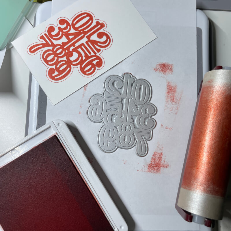 Papier mit rotem Folienabdruck eines Schriftzugs auf weißem Papier