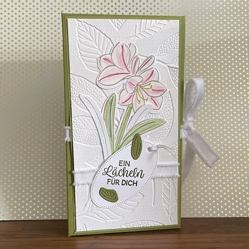 Frühlingsvariante der Schachtel: geprägter weißer Aufleger mit rosa Amaryllis, weißes Band und Anhänger mit Grußtext