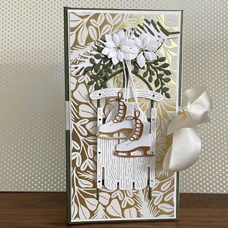 Fertige Buchschachtel mit grün-goldenem Designerpapier, weißen Blüten, Schlittschuhen und Satinschleife von Stampin' Up!