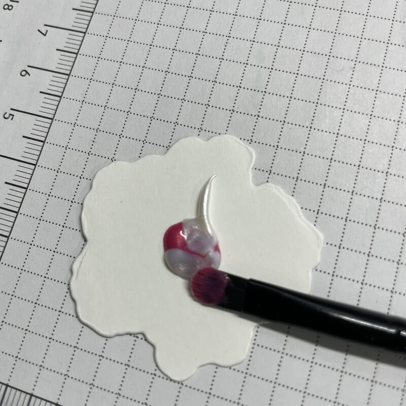 Ein Klecks Emaille-Gel wird mit dem Pinsel auf das Blütenstanzteil aufgetragen