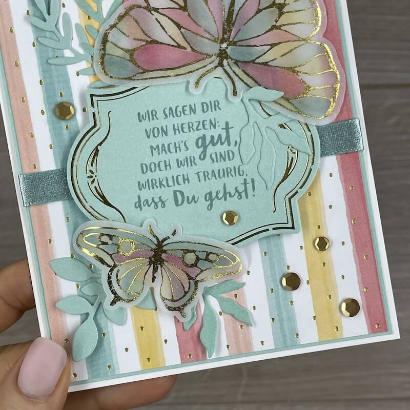 Karte mit großem goldakzentuiertem Schmetterling und Spruch in der Hand