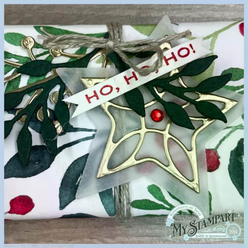 Detail einer Verpackung mit goldenem Stern, Ho-ho-ho-Etikett und roten Beeren
