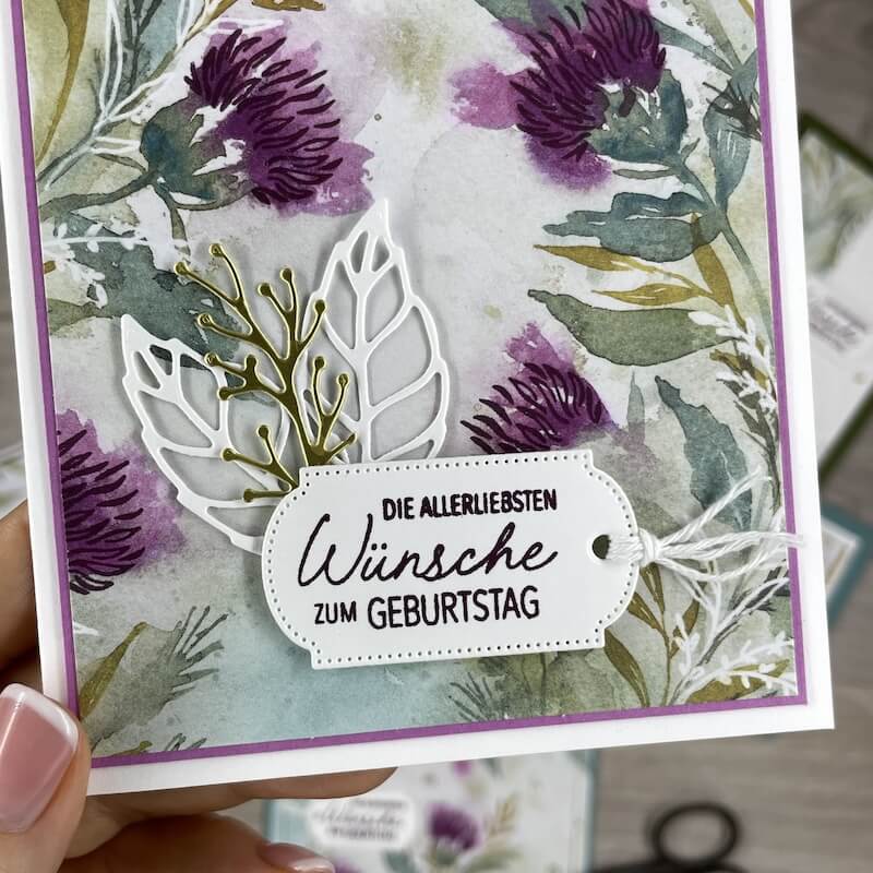 Nahaufnahme: weiße Blattstanzteile und Grußetikett auf dem Blumenpapier