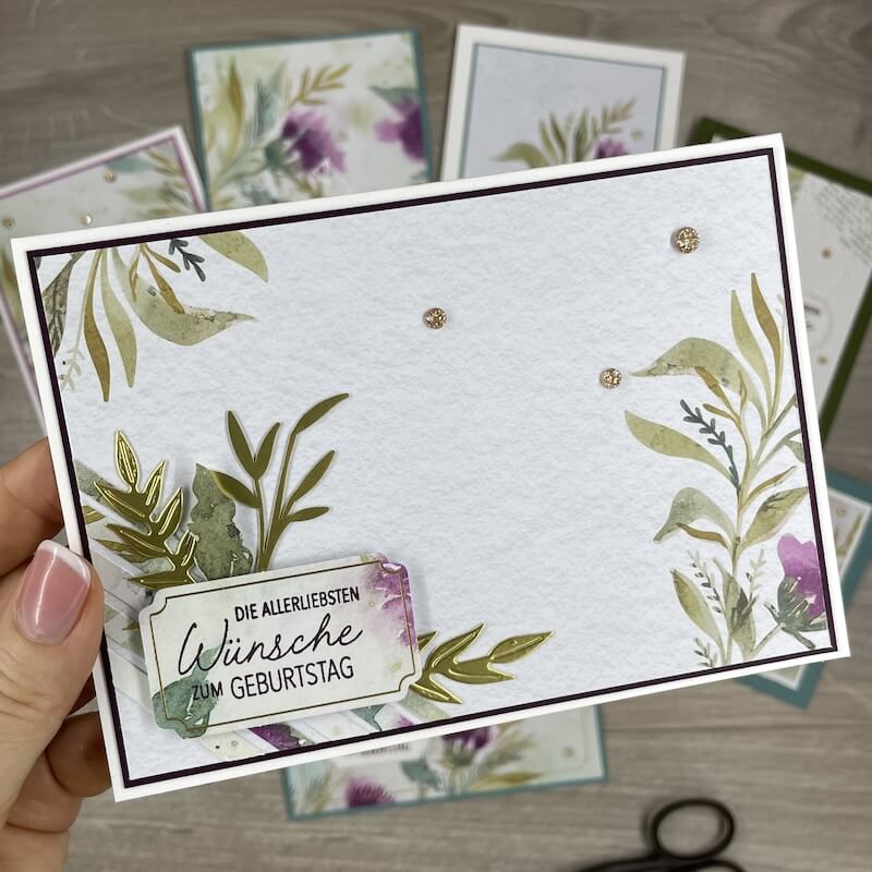 Fertige Karte in der Hand mit floralen Ecken und goldenen Akzenten