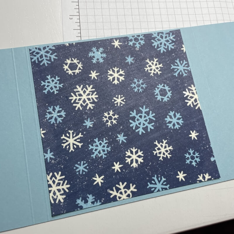 Dunkelblaues Schneeflockenpapier in der Mitte der Grundkarte aufgeklebt