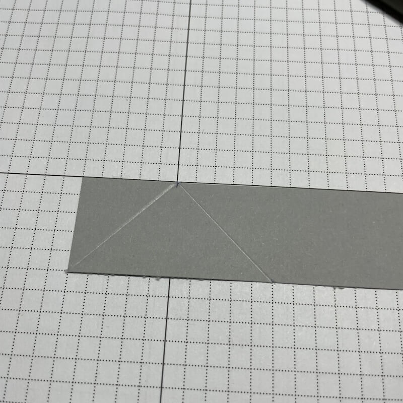 Derselbe Streifen mit zwei diagonalen Falzlinien, die von der unteren Ecke zu den Markierungen laufen