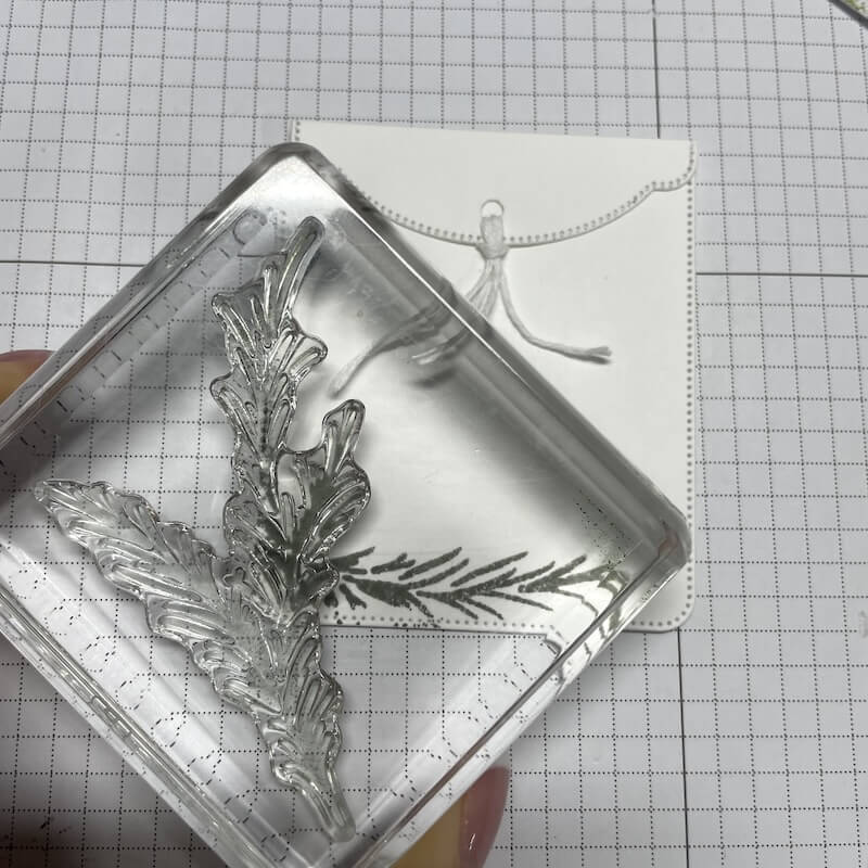 Acrylblock mit Zweigstempel über der weißen Hülle für die Geschenkkarte