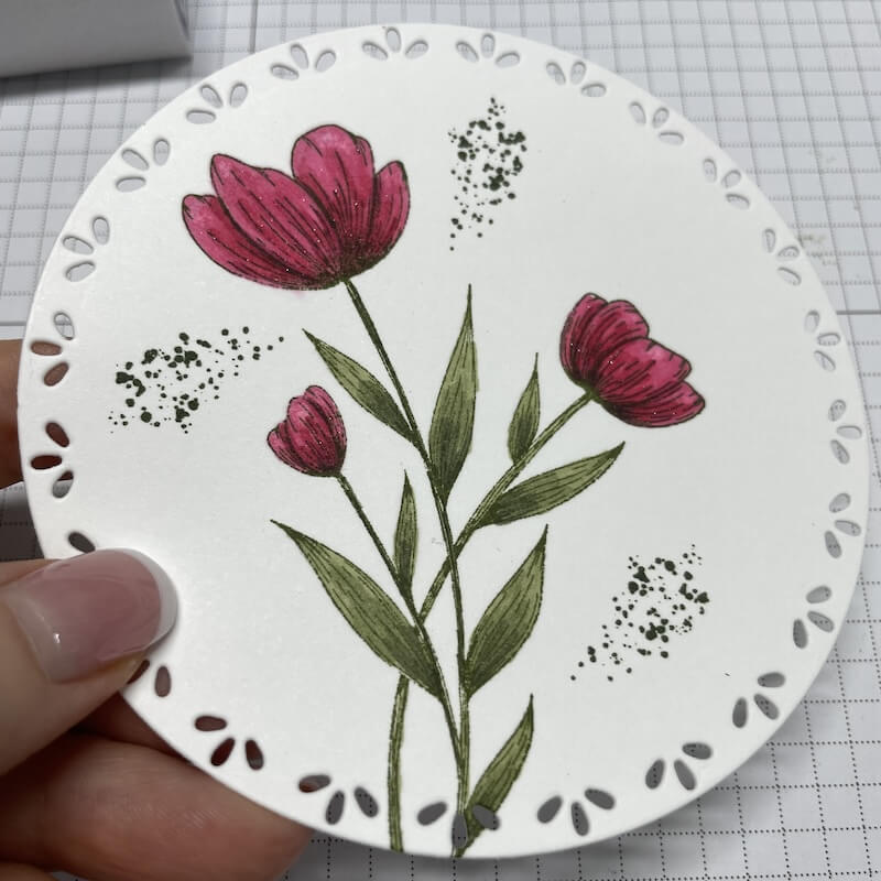 Koloriertes Tulpenmotiv auf gestanztem Kreis mit Lochrand in der Hand