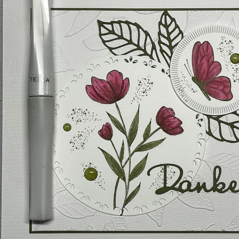 Ein Glitzerstift bringt Glanz auf die kolorierten Blüten der Banderole