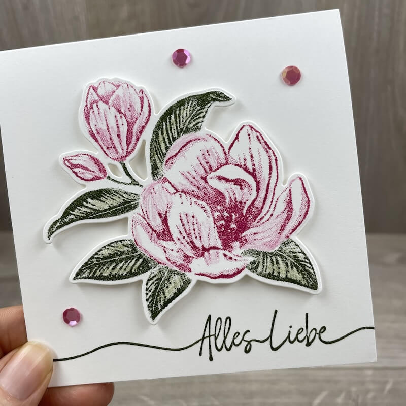 Karte mit gestempelter Magnolie in Pink, dunkelgrünen Blättern und dem Gruß Alles Liebe