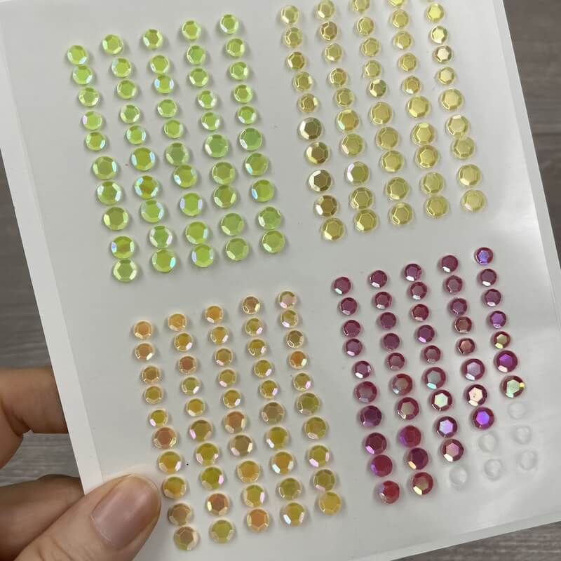 Selbstklebende Schimmerpailletten in Grün, Gelb, Bernstein, Pink und Klar auf dem Trägerbogen