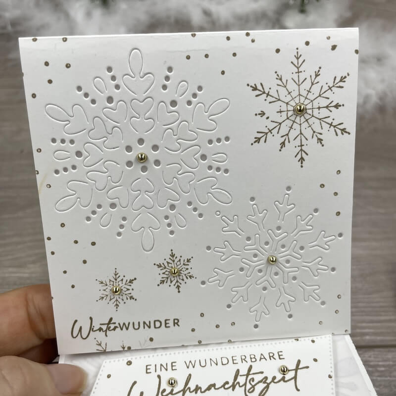 Teelichtkarte mit ausgestanzten goldakzentuierten Schneeflocken in der Hand