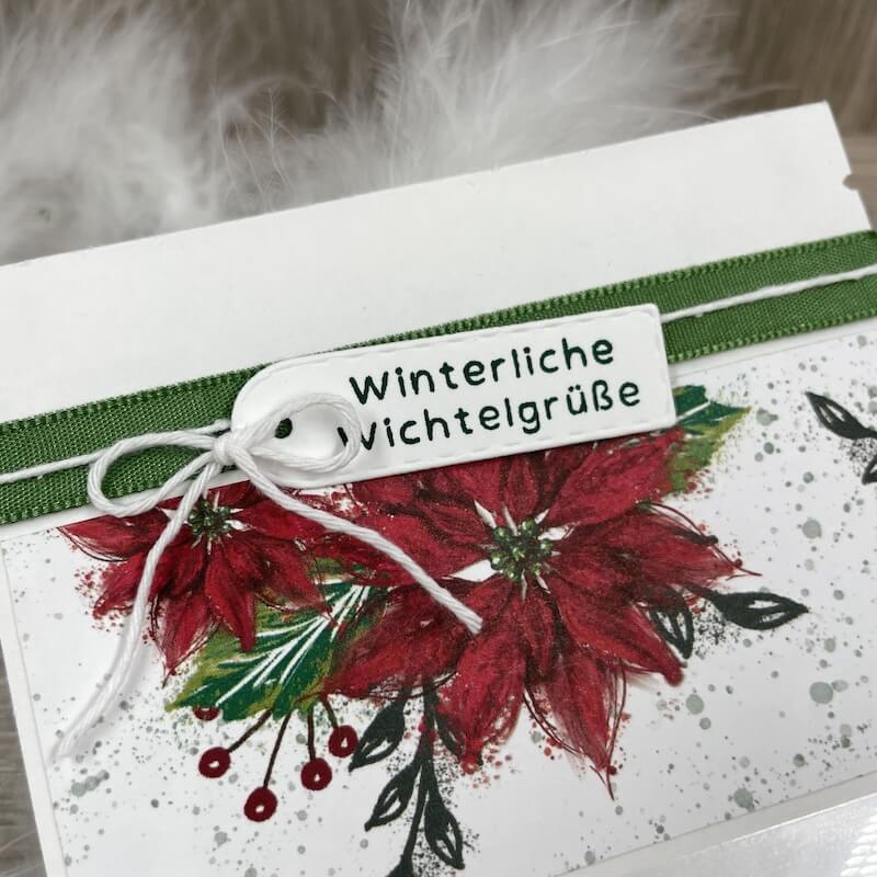 Detail des Winterliche-Wichtelgrüße-Etiketts mit roten Weihnachtssternen und Band
