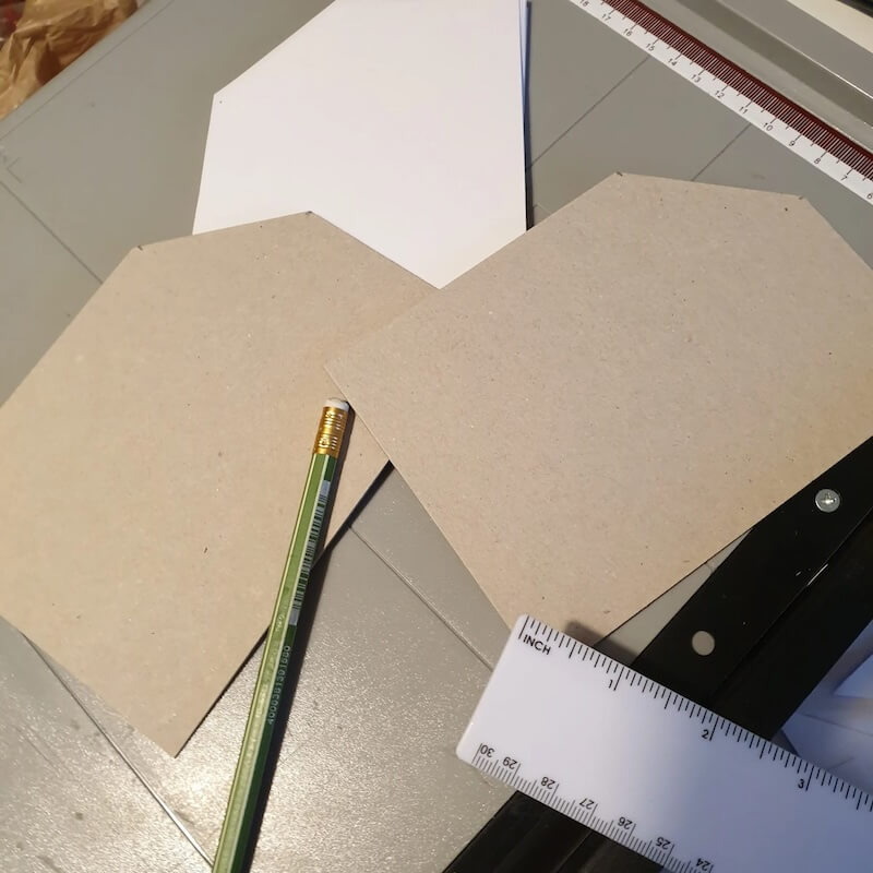Zwei aufgeklappte Graupappen mit Bleistift und Lineal