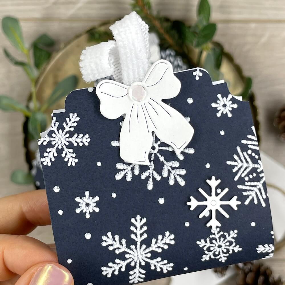 Mitbringsel für Weihnachten aus tiefseeblauem Designerpapier mit weißer Schleife und geprägten Schneeflocken