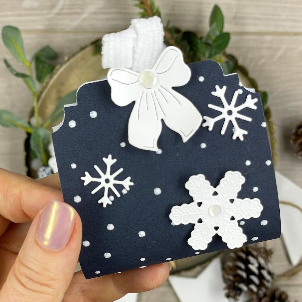 Fertiges Mitbringsel zu Weihnachten mit weißer Schleife, Schneeflocken und Schmuckecken