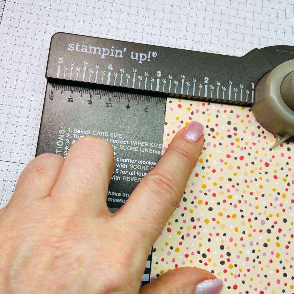 Konfetti-Designerpapier wird am Falzbrett für Umschläge bei 7 cm angelegt