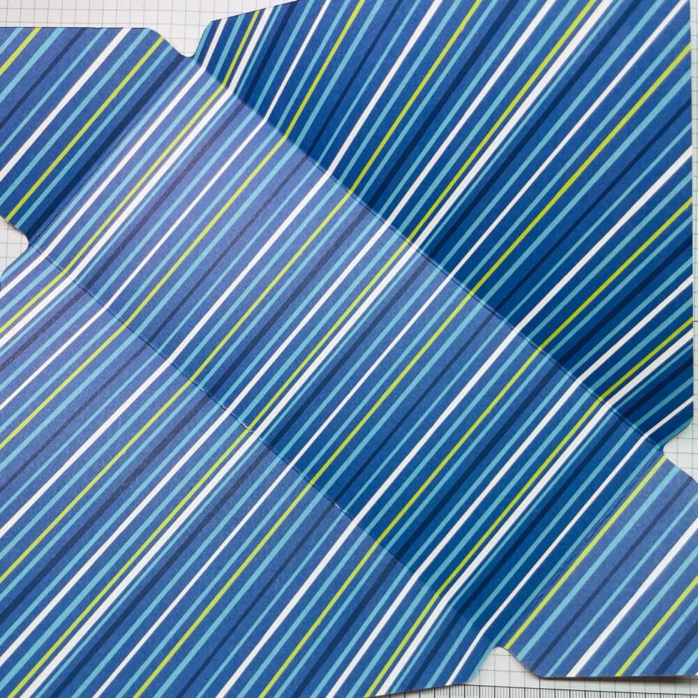 Gefalzte Grundform des Umschlags aus blau gestreiftem Designerpapier mit breiten Seitenklappen