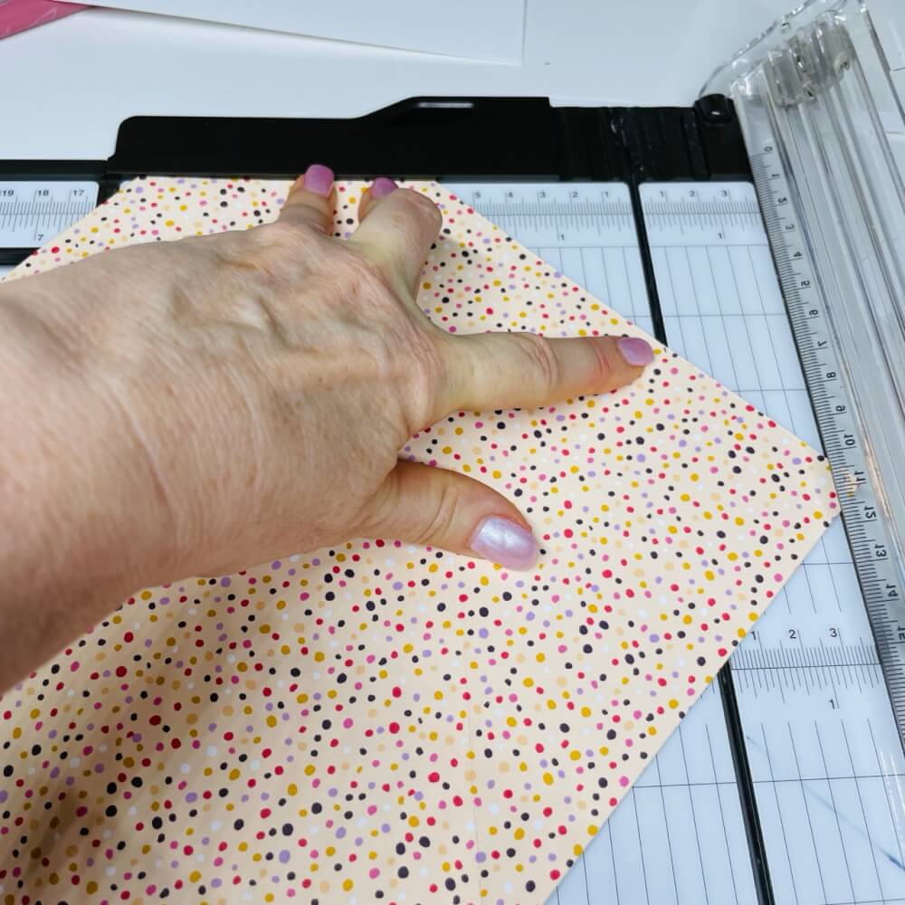 Der Umschlag aus Konfetti-Papier liegt zum Kürzen der zweiten Klappe im Papierschneider