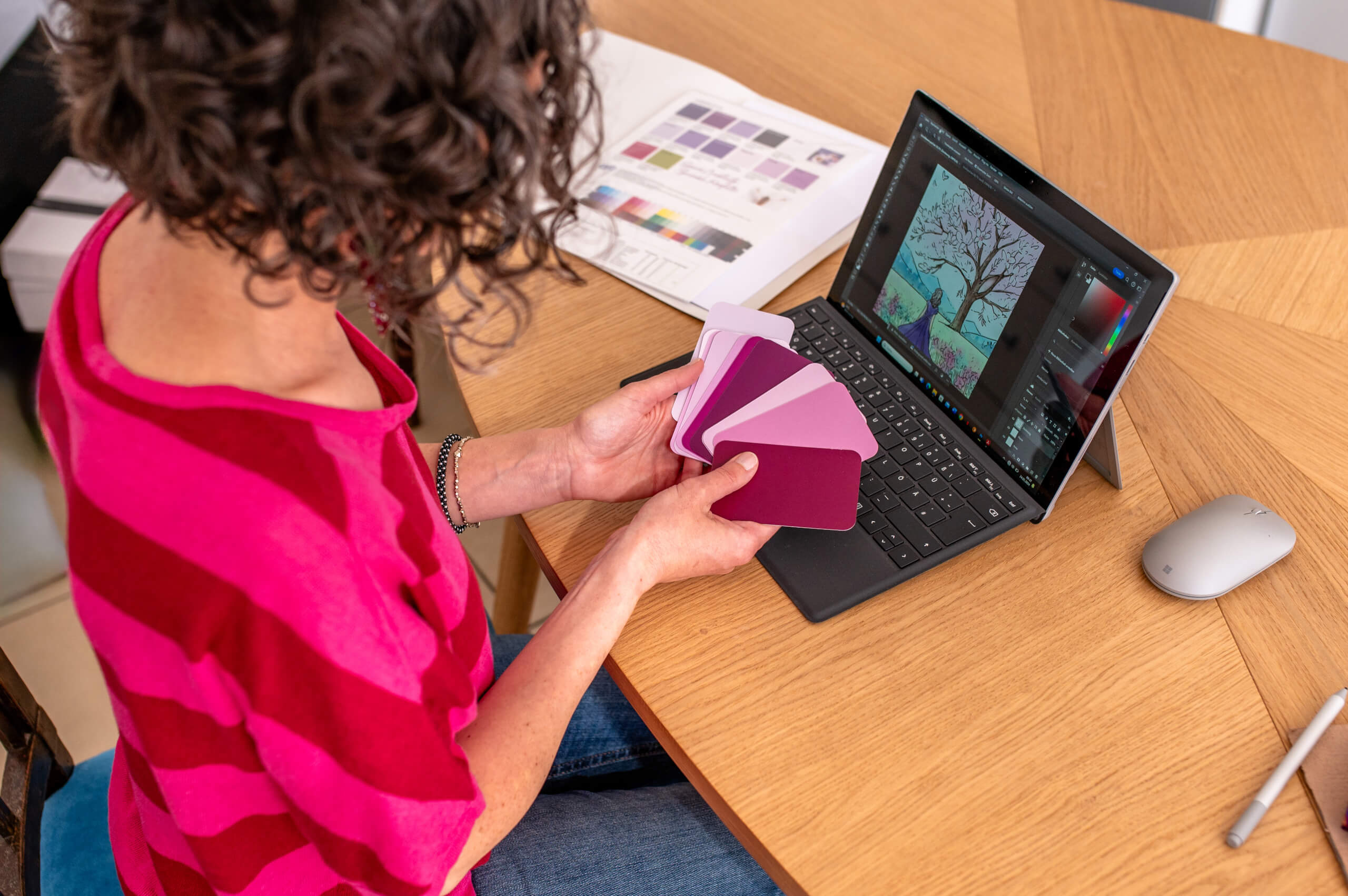 Annika Lind arbeitet am Laptop und hält Farbmustern für ein Brandingprojekt