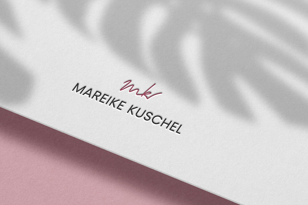 Logo-Detail mit roter handschriftlicher Signatur und klarer Wortmarke auf hellem Papier.