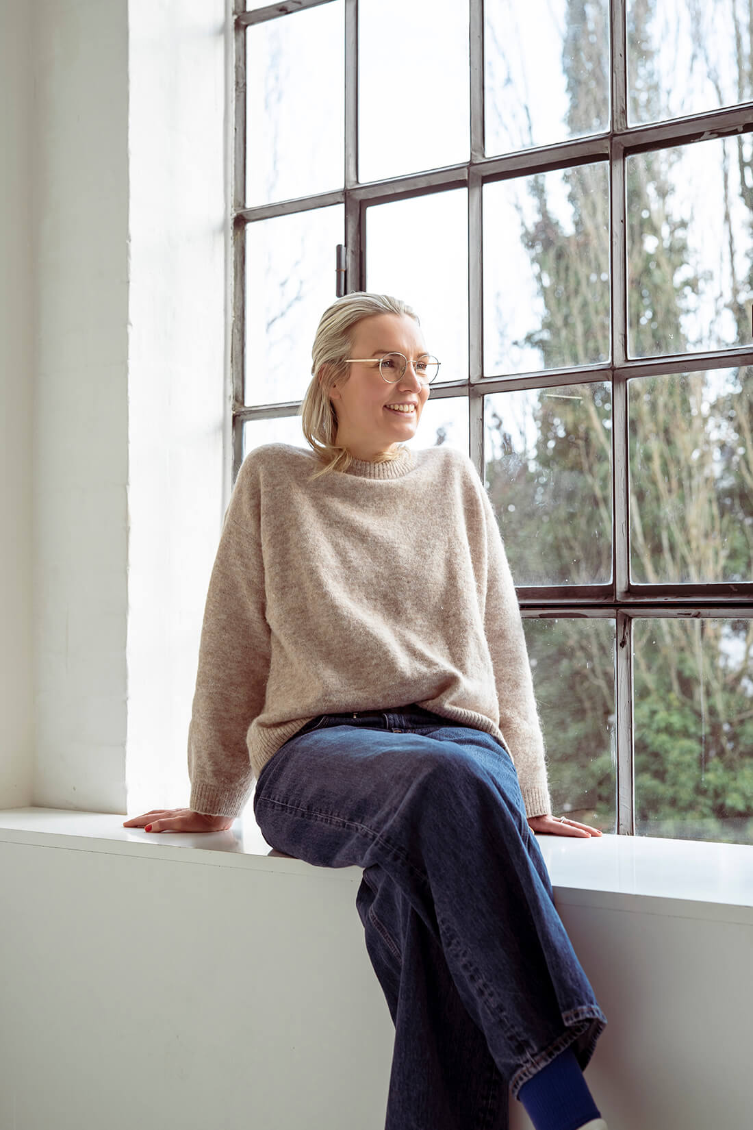 Birthe Claussen, Heilpraktikerin für Psychotherapie in Ebstorf, sitzend auf einer Fensterbank und freundlich lächelnd.