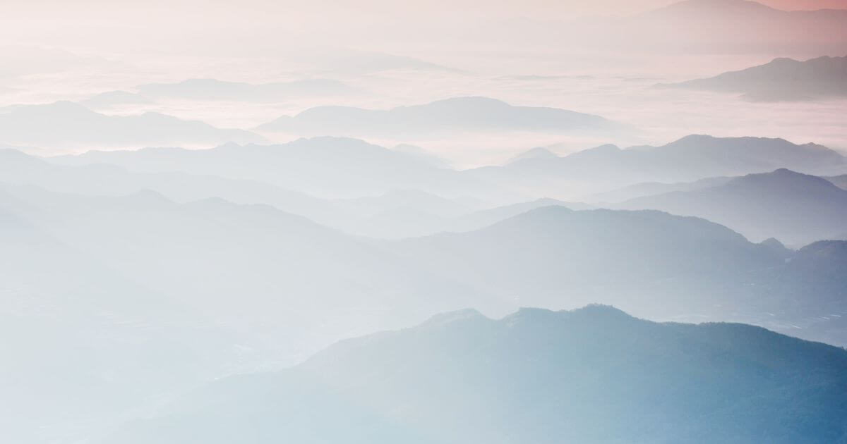 Mehrschichtige Berglandschaft im weichen Morgenlicht – symbolisches Bild für einen Lebensübergang, innere Veränderung und Phasen zwischen Vertrautem und Neuem.
