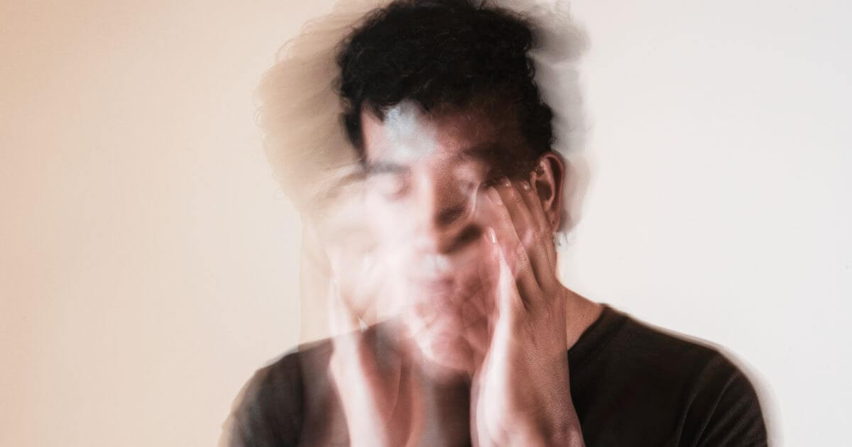 Mehrfachbelichtete Darstellung einer Person mit Händen im Gesicht – symbolisches Bild für Gedankenkreisen, psychische Überforderung und typische Symptome von Überlastung.