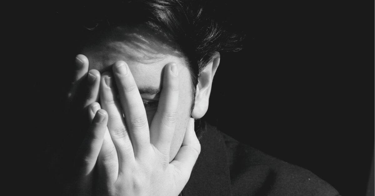 Person bedeckt ihr Gesicht mit den Händen – symbolisches Bild für Scham, Rückzug und emotionale Belastung in Krisen.