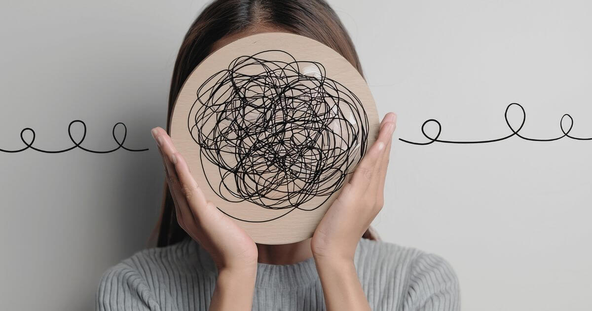 Person hält eine runde Fläche mit chaotischen Linien vor das Gesicht – symbolisches Bild für Überforderung, Gedankenkreisen und mentale Überlastung.