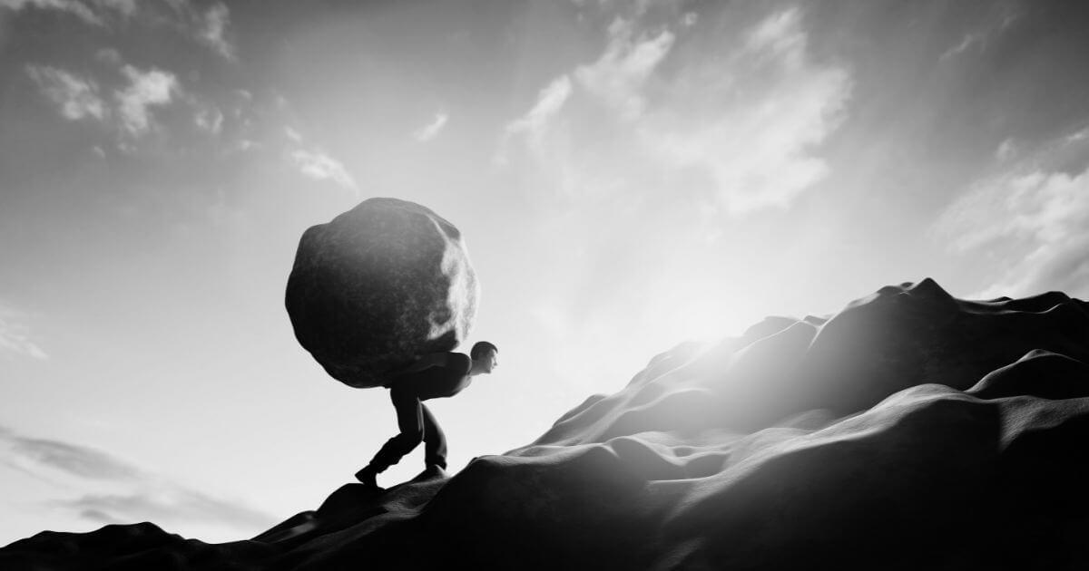 Zu viel zumuten und Grenzen übergehen: symbolische Darstellung einer Person, die eine schwere Last einen Berg hinaufträgt.