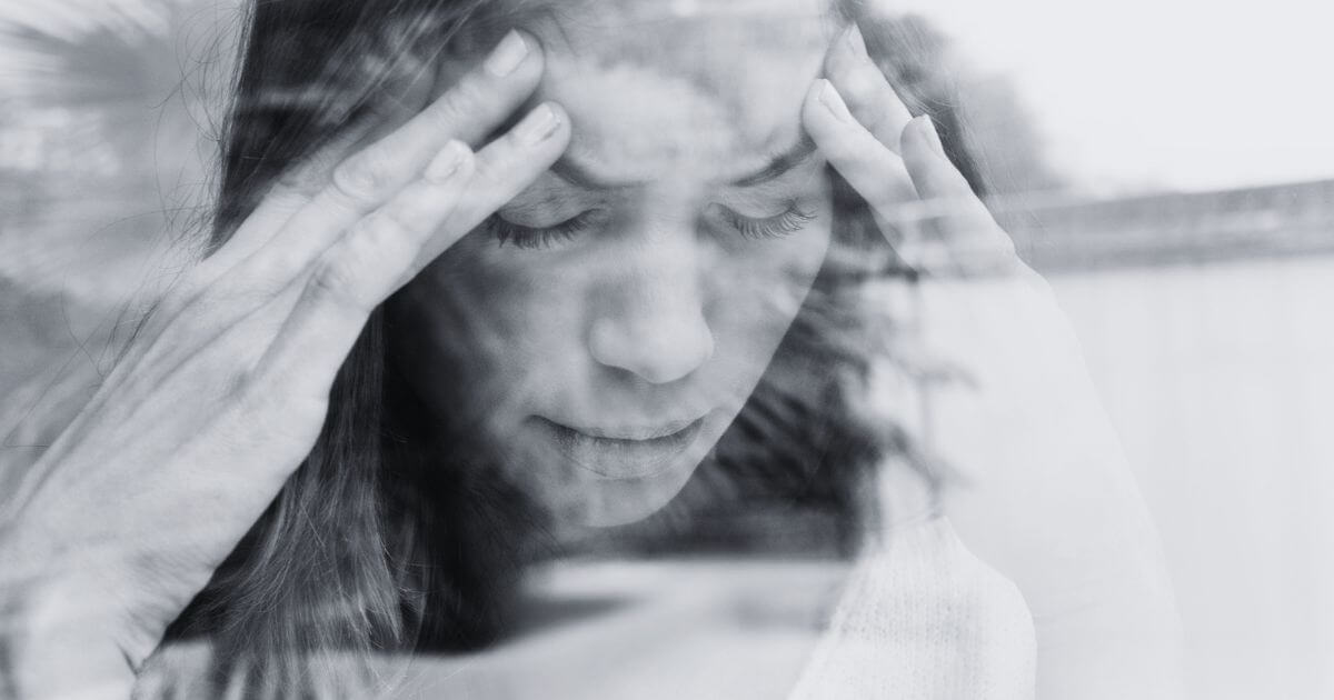 Frau mit geschlossenen Augen und Händen an den Schläfen – symbolisches Bild für körperliche Symptome bei psychischer Belastung und Stress.