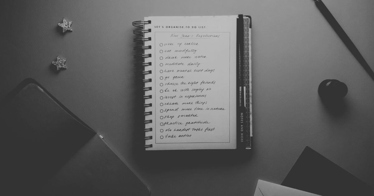 Schwarz-Weiß-Aufnahme eines Notizbuchs mit langer To-do-Liste auf einem Schreibtisch – symbolisches Bild für Entscheidungsstress und die Schwierigkeit, Prioritäten zu setzen.